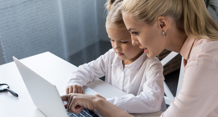 beautiful blonde mother and daughter using laptop together