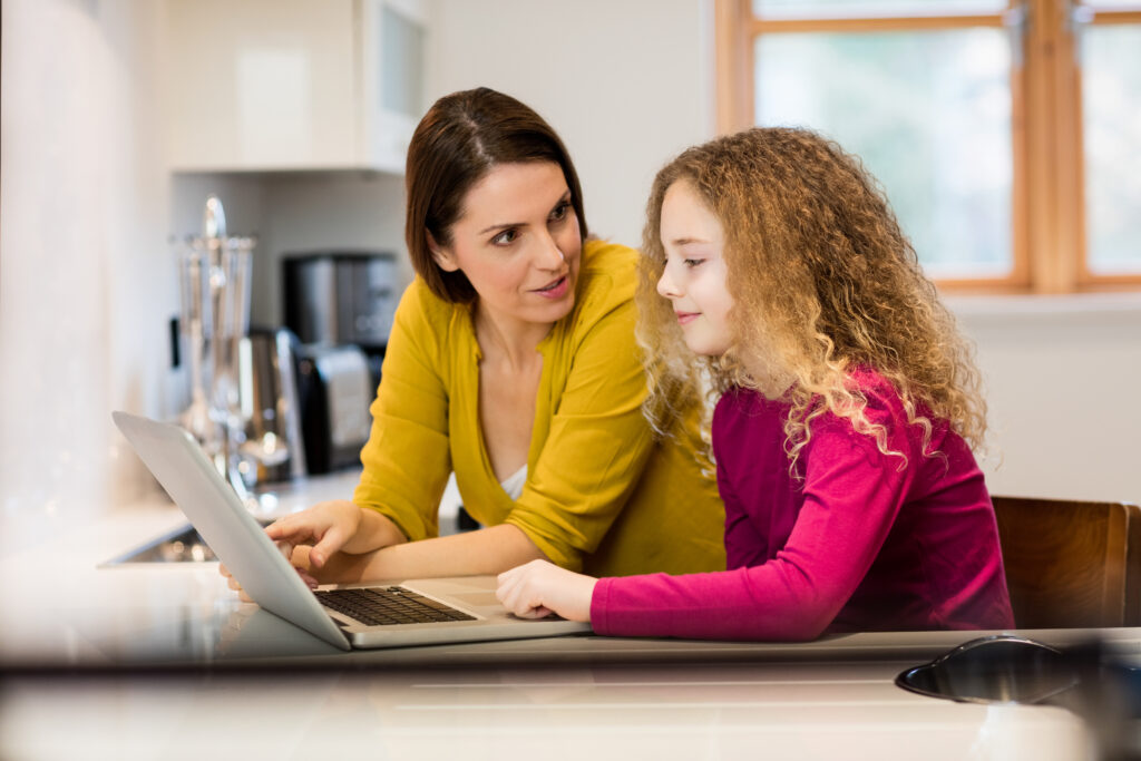 Mother and daughter using laptop in kitchen