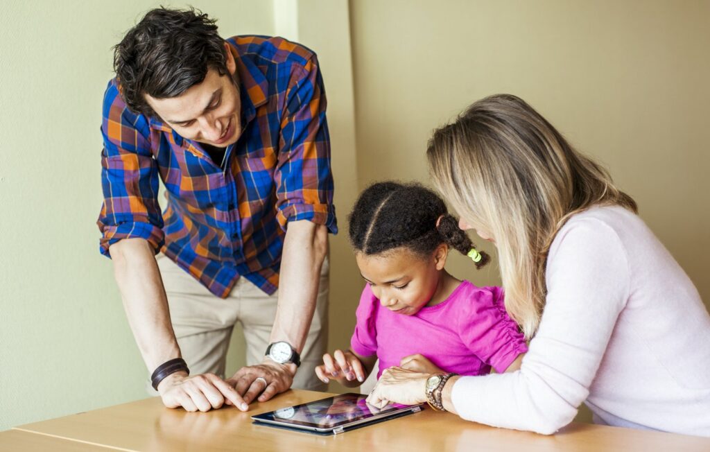 Teachers with girl painting on tablet computer in classroom